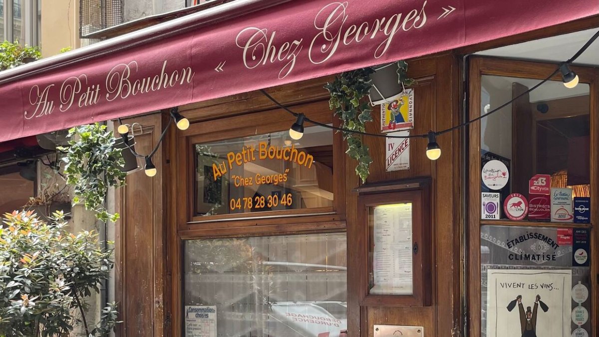 La devanture en bois et son auvent bordeaux de l’Au Petit Bouchon « Chez Georges », bouchon lyonnais près de l’Opéra