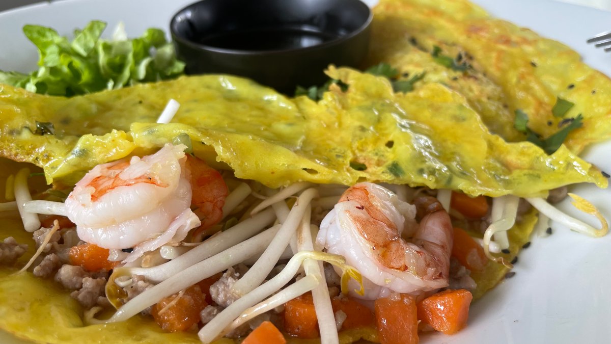 Un bánh xèo croustillant garni de crevettes, de germes de soja et de carottes, servi avec une sauce au restaurant Au Piment Poivré à Lyon Un bánh xèo croustillant garni de crevettes, de germes de soja et de carottes, servi avec une sauce au restaurant Au Piment Poivré à Lyon