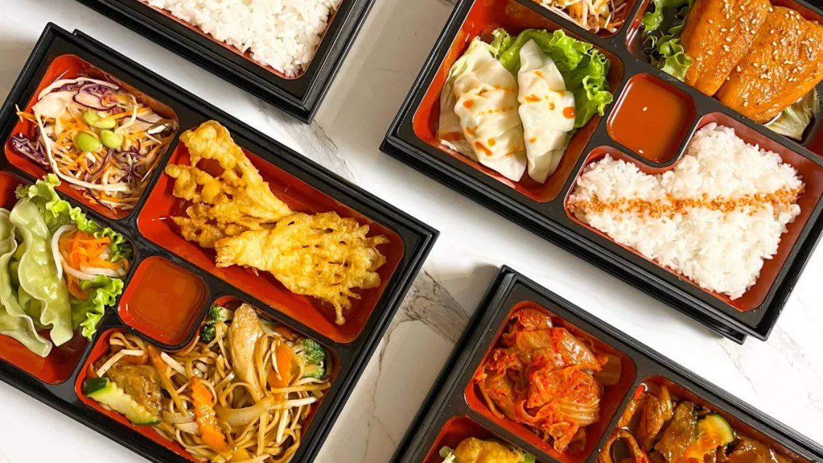 Deux bento box garnis de raviolis, riz, salade et beignets, servis chez Bentogo, restaurant à Lyon