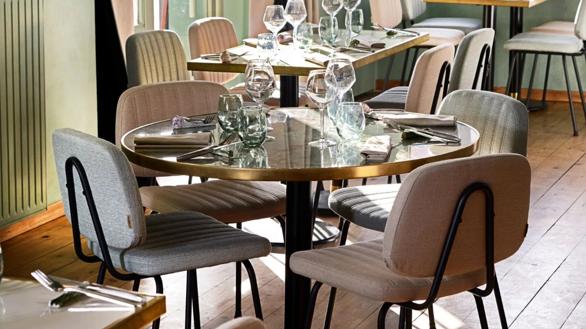 La salle du restaurant Bergamote à Lyon, avec ses tables en bois, ses verres sur la table et ses chaises en velours rose et gris La salle du restaurant Bergamote à Lyon, avec ses tables en bois, ses verres sur la table et ses chaises en velours rose et gris