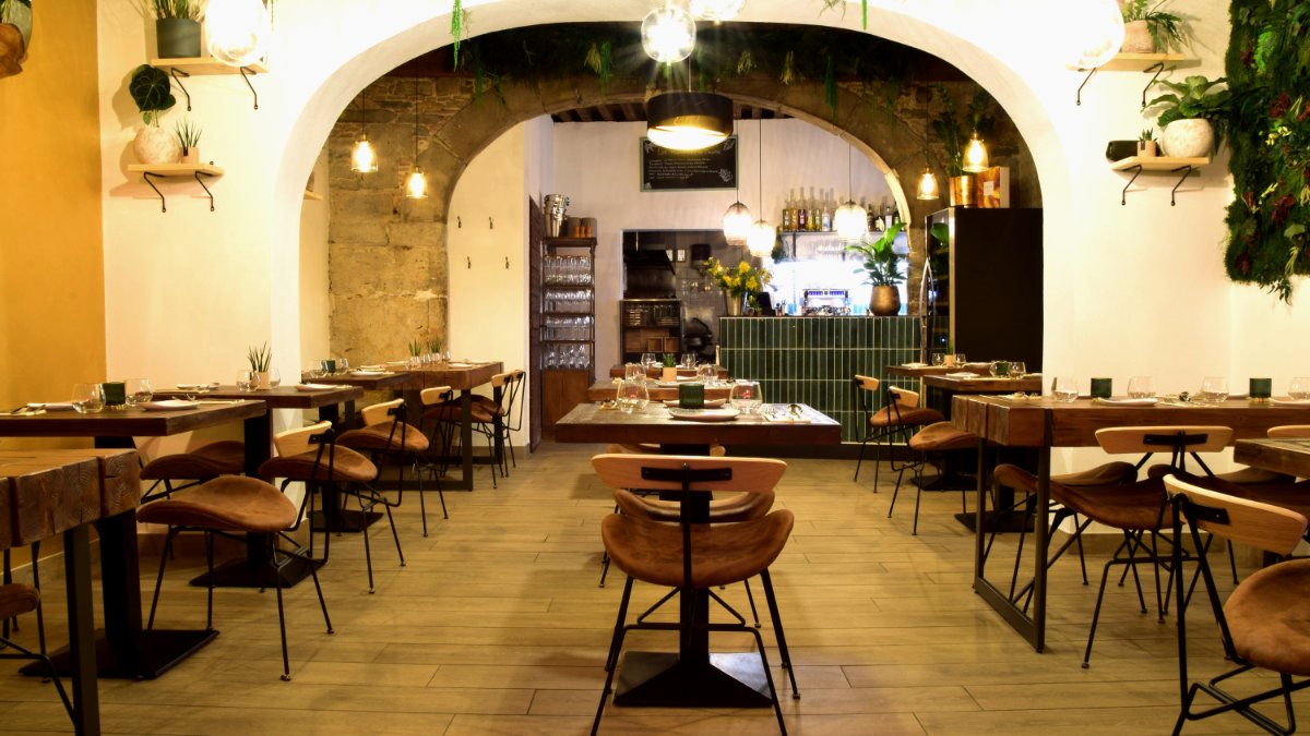 La salle voûtée en pierre de Canopée à Lyon, avec ses tables en bois, ses chaises en cuir et son comptoir en carreaux verts La salle voûtée en pierre de Canopée à Lyon, avec ses tables en bois, ses chaises en cuir et son comptoir en carreaux verts
