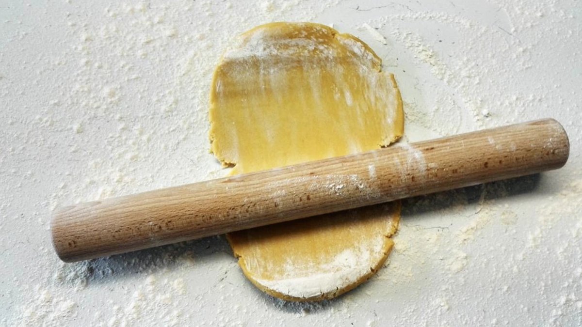 Un rouleau à pâtisserie en bois sur une pâte farinée, lors d’un cours de cuisine chez Chef Lyon