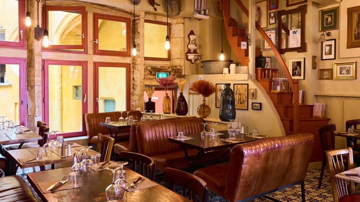 La salle chaleureuse de Chez Grand-Père, avec ses banquettes en cuir, ses tables en bois et ses cadres anciens, dans le Vieux Lyon