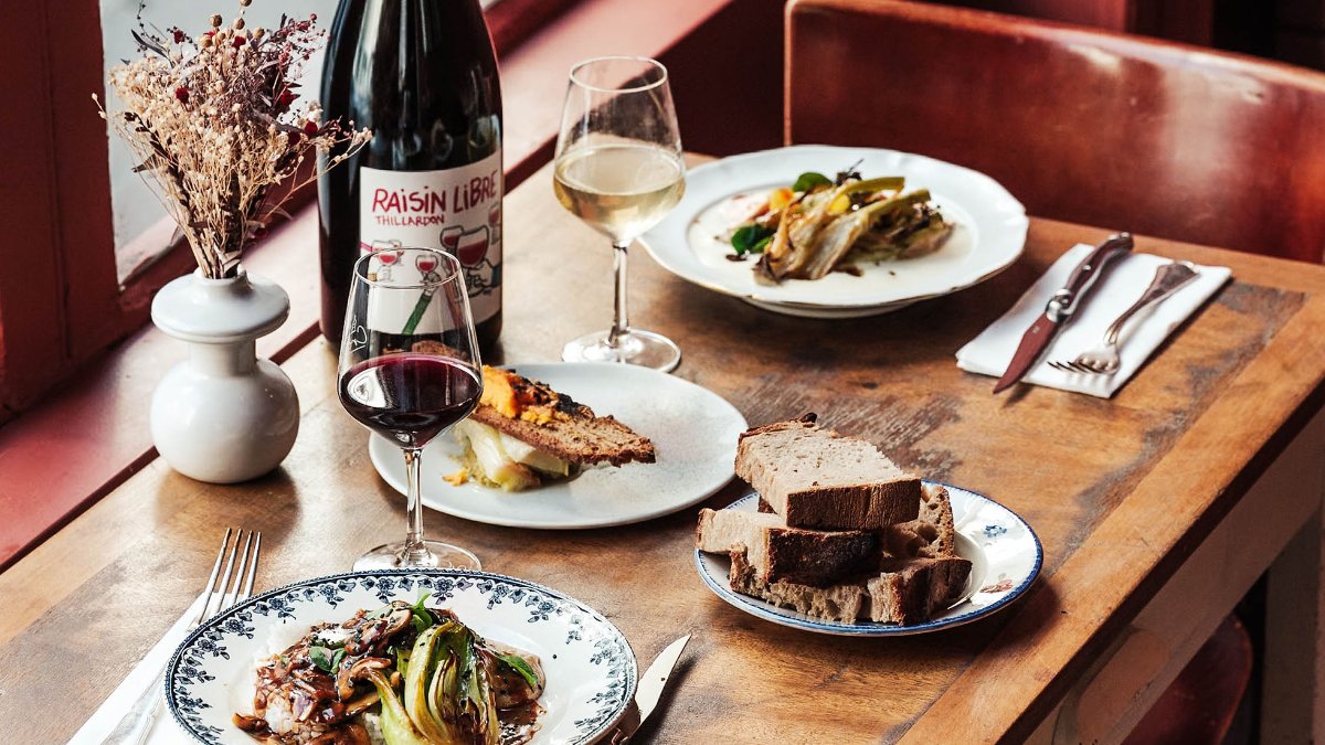 Une table dressée chez Croûton, à Lyon : assiettes de saison, vin rouge et pain Une table dressée chez Croûton, à Lyon : assiettes de saison, vin rouge et pain