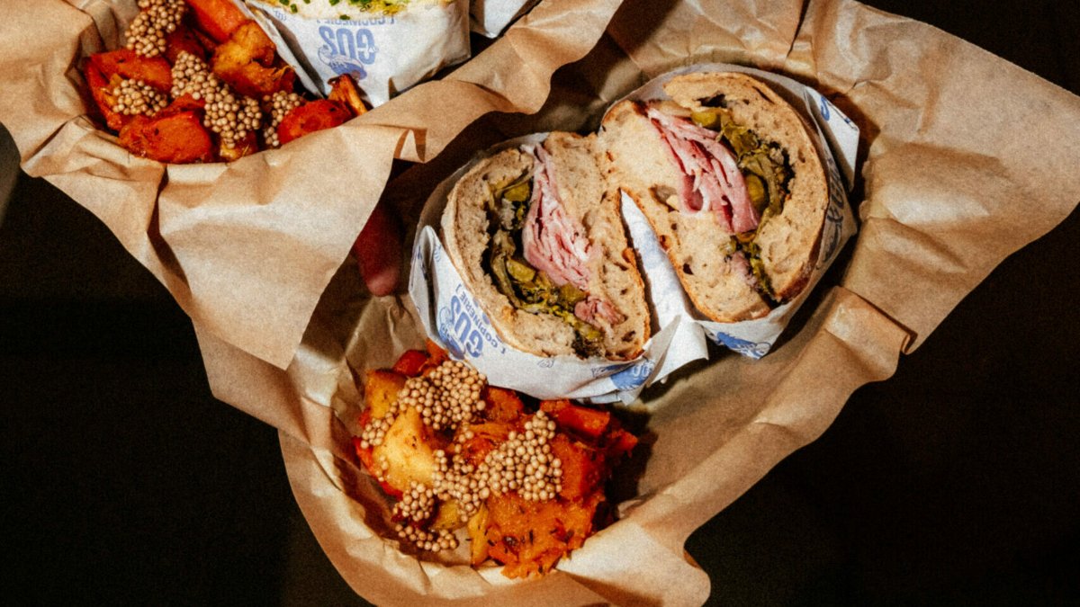 Deux sandwichs artisanaux posés sur du papier kraft avec leurs accompagnements de patates douces, chez Gus & Gas à Lyon