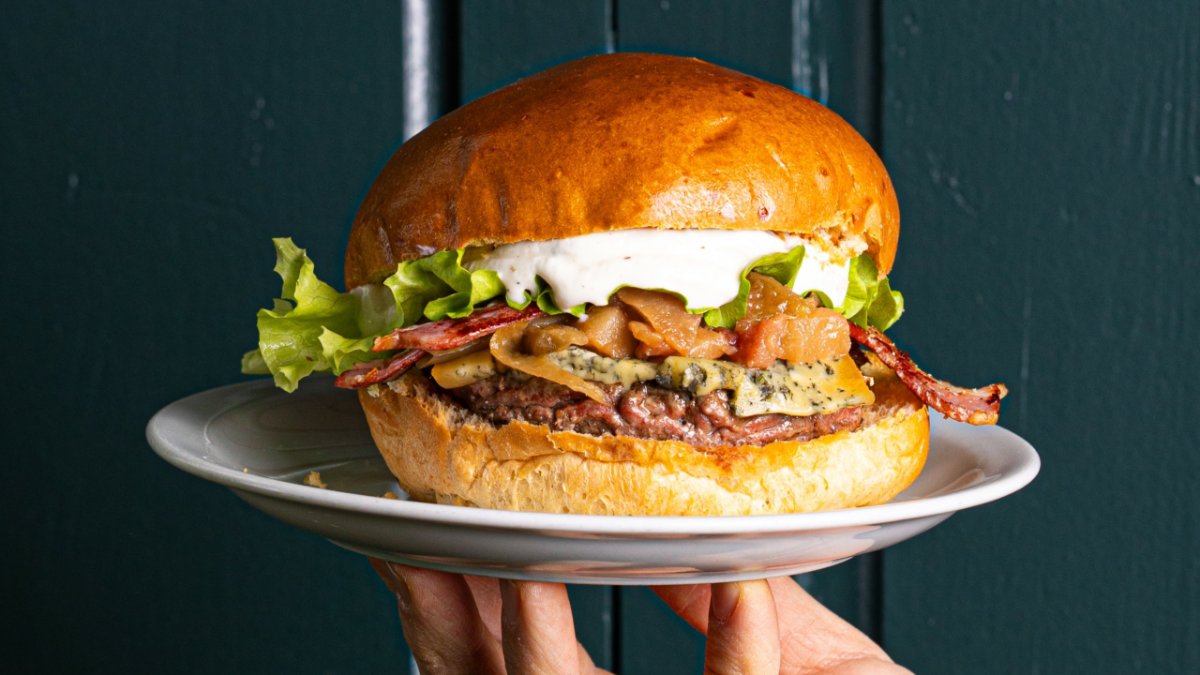 Un burger généreux au bacon et à la sauce blanche dans un pain brioché, servi sur une assiette, chez Kaffee Berlin à Lyon Un burger généreux au bacon et à la sauce blanche dans un pain brioché, servi sur une assiette, chez Kaffee Berlin à Lyon