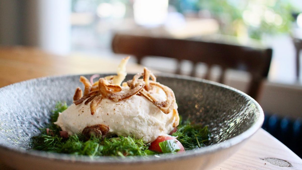 Un plat de poisson sur lit d’herbes et tomates, servi dans une assiette creuse en grès, au restaurant L’Écume à Lyon Un plat de poisson sur lit d’herbes et tomates, servi dans une assiette creuse en grès, au restaurant L’Écume à Lyon