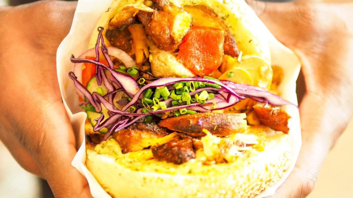 Un kebab maison garni de viande grillée, de légumes et de chou rouge, tenu à deux mains, chez La Broche Un kebab maison garni de viande grillée, de légumes et de chou rouge, tenu à deux mains, chez La Broche