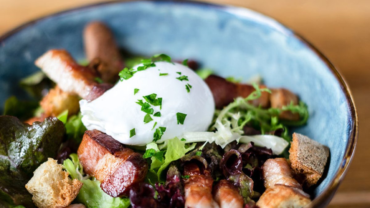 Une salade lyonnaise au lard, croûtons et œuf poché dans un bol bleu au Bouchon des Artistes, bouchon à Lyon Une salade lyonnaise au lard, croûtons et œuf poché dans un bol bleu au Bouchon des Artistes, bouchon à Lyon