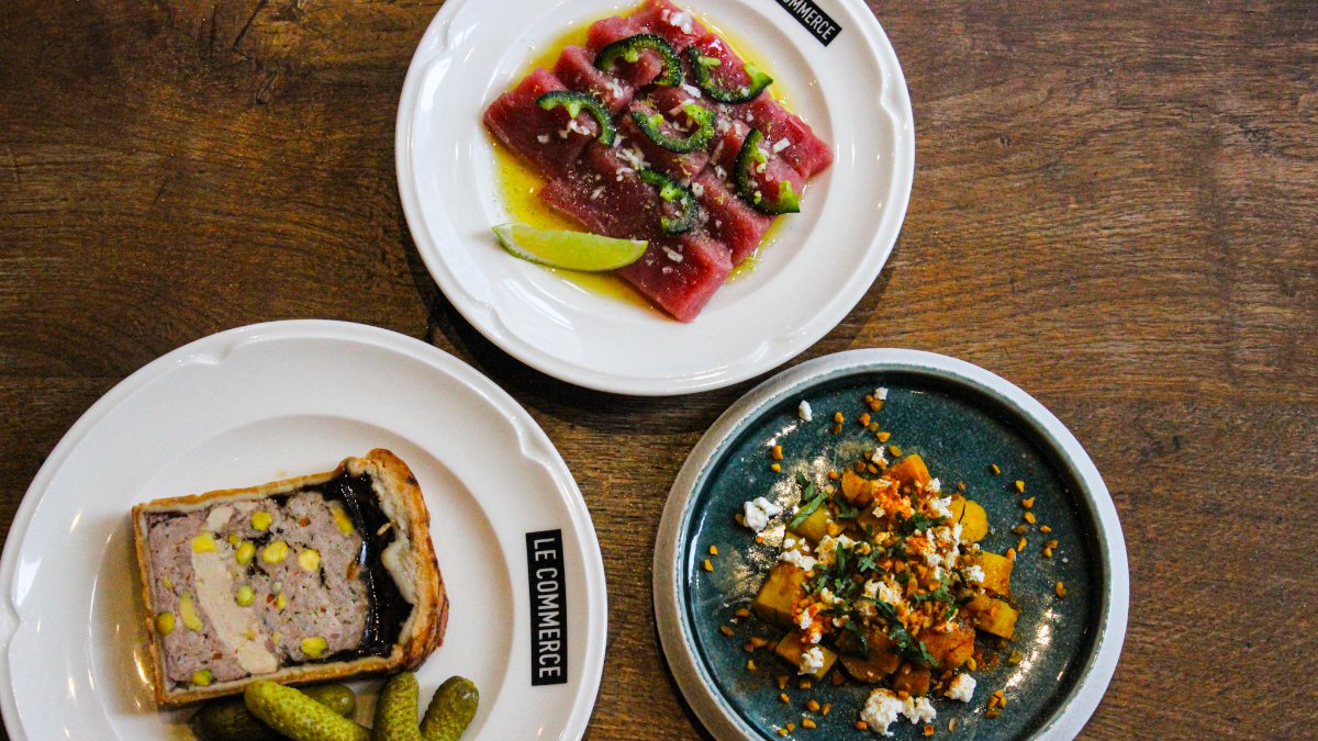 Trois assiettes de tapas vues du dessus sur une table en bois : tartare de thon, terrine en croûte et salade, au bistro Le Commerce à Lyon Trois assiettes de tapas vues du dessus sur une table en bois : tartare de thon, terrine en croûte et salade, au bistro Le Commerce à Lyon