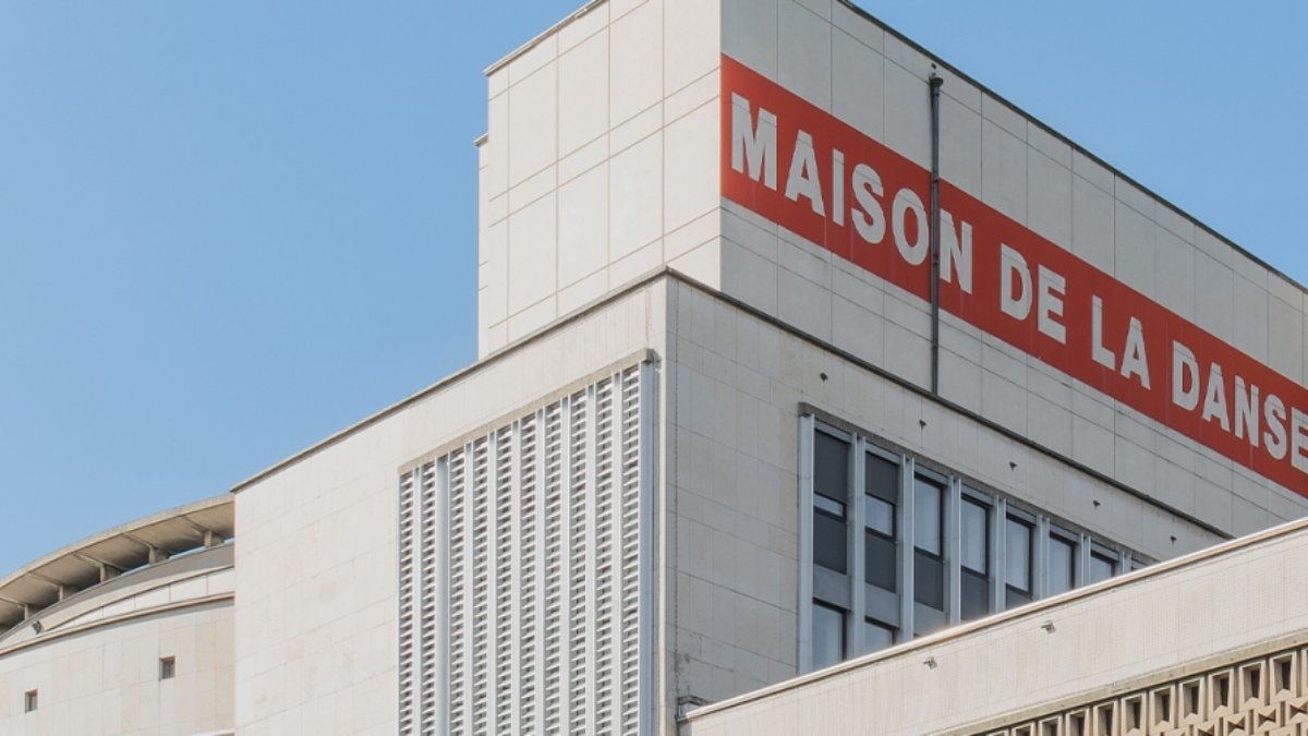 La façade de la Maison de la Danse à Lyon, avec son enseigne rouge « Maison de la Danse » sur le bâtiment clair