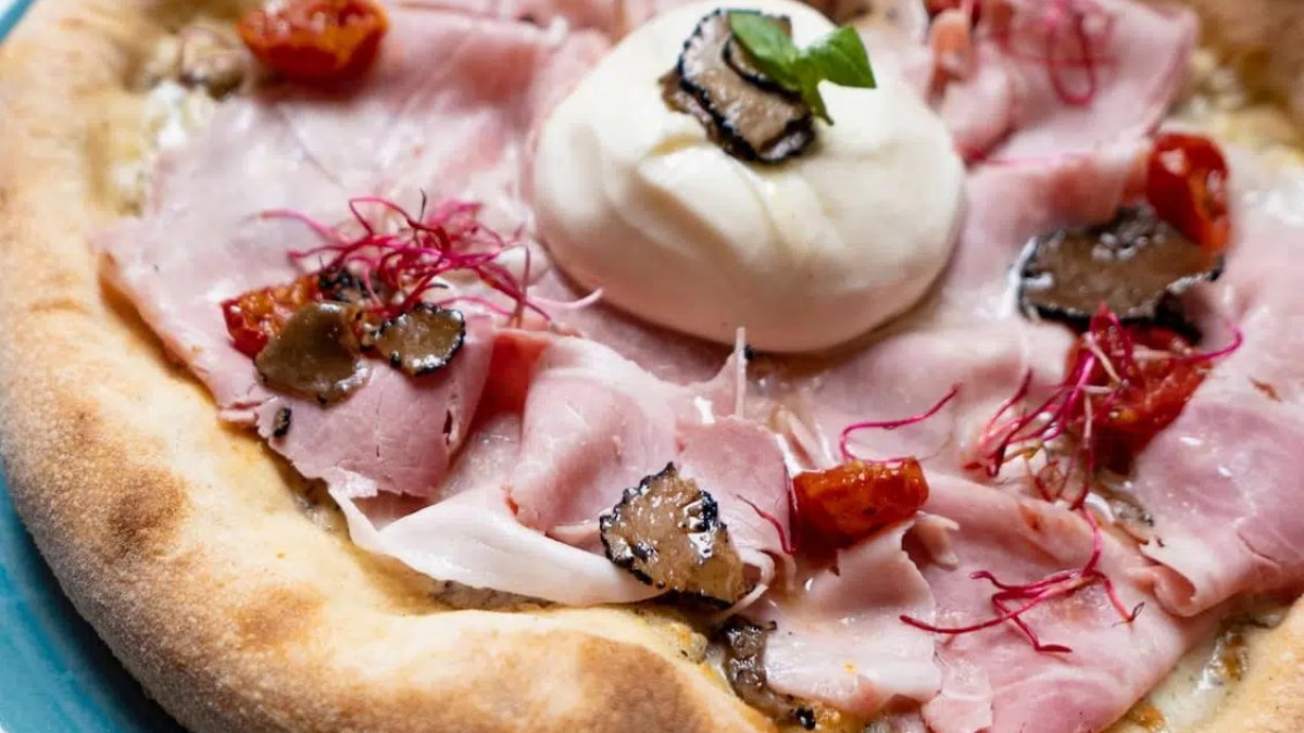 Gros plan sur une pizza au jambon, burrata, truffe noire et tomates cerises chez Mamma Osteria à Lyon Gros plan sur une pizza au jambon, burrata, truffe noire et tomates cerises chez Mamma Osteria à Lyon