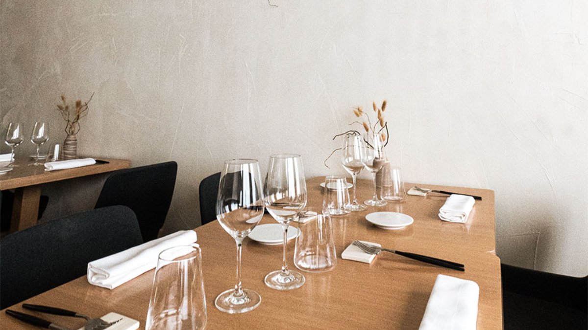 Une table dressée avec verres à pied, serviettes blanches et fleurs séchées dans la salle de Mertensia, restaurant à Lyon Une table dressée avec verres à pied, serviettes blanches et fleurs séchées dans la salle de Mertensia, restaurant à Lyon
