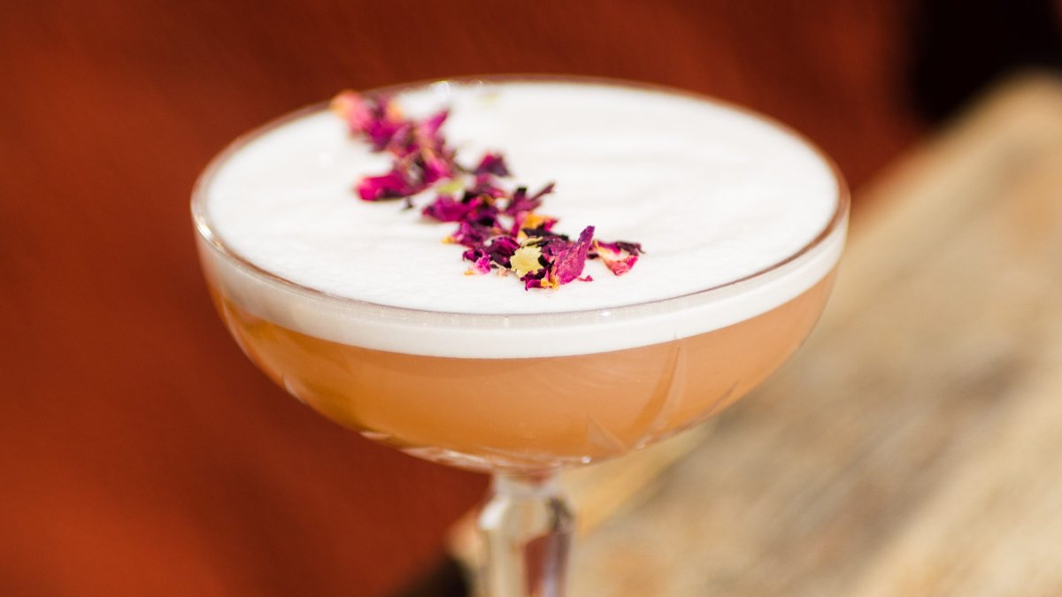 Un cocktail mousseux décoré de pétales de rose séchés dans une coupe, au Momento Coffee à Lyon