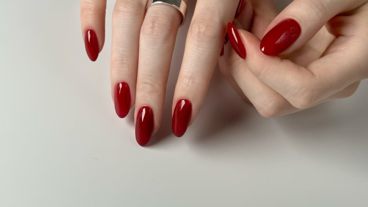 Des mains aux ongles longs vernis de rouge foncé, photo du site du salon See U Nails à Lyon Des mains aux ongles longs vernis de rouge foncé, photo du site du salon See U Nails à Lyon